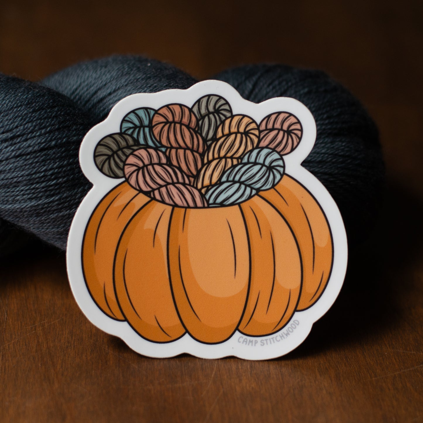 Sticker of a pumpkin with yarn balls on a dark background