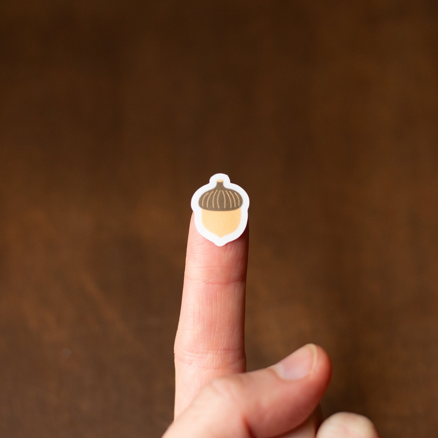 Finger with a sticker of an acorn on a brown background