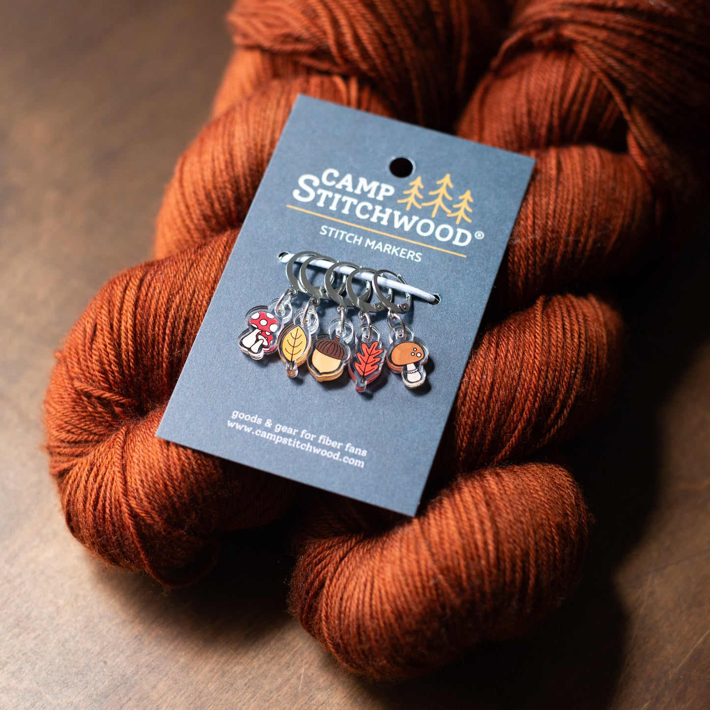 Fall forest stitch markers on a card with skein of yarn