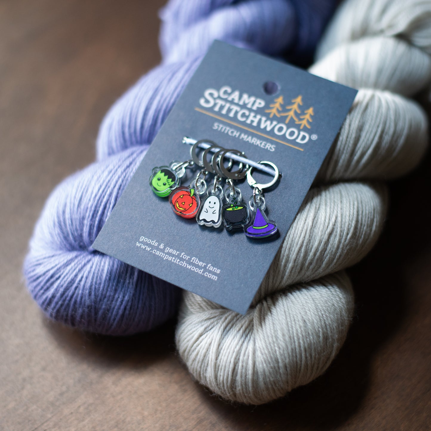 A set of Halloween stitch markers on purple and gray yarn
