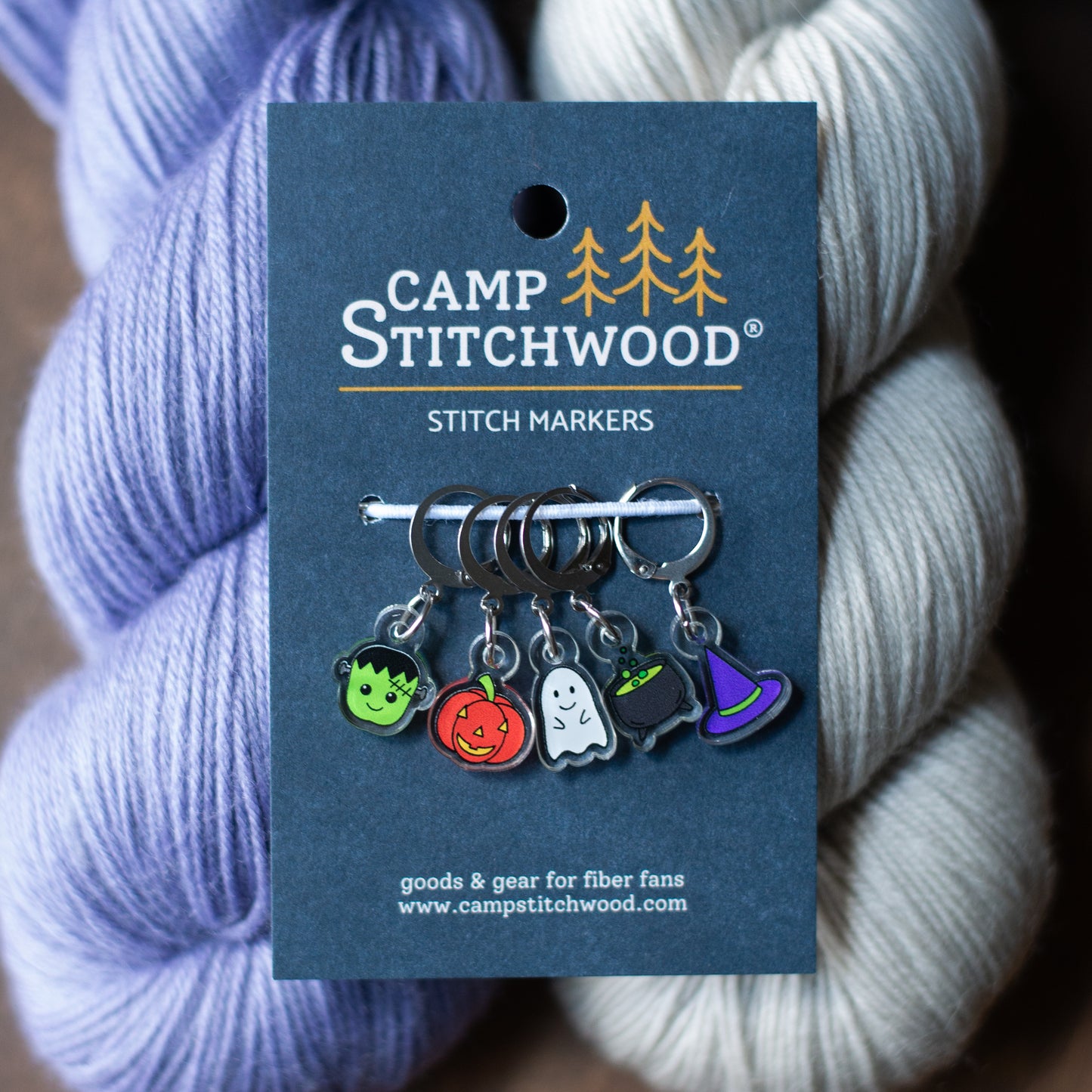 A set of Halloween stitch markers on purple and gray yarn