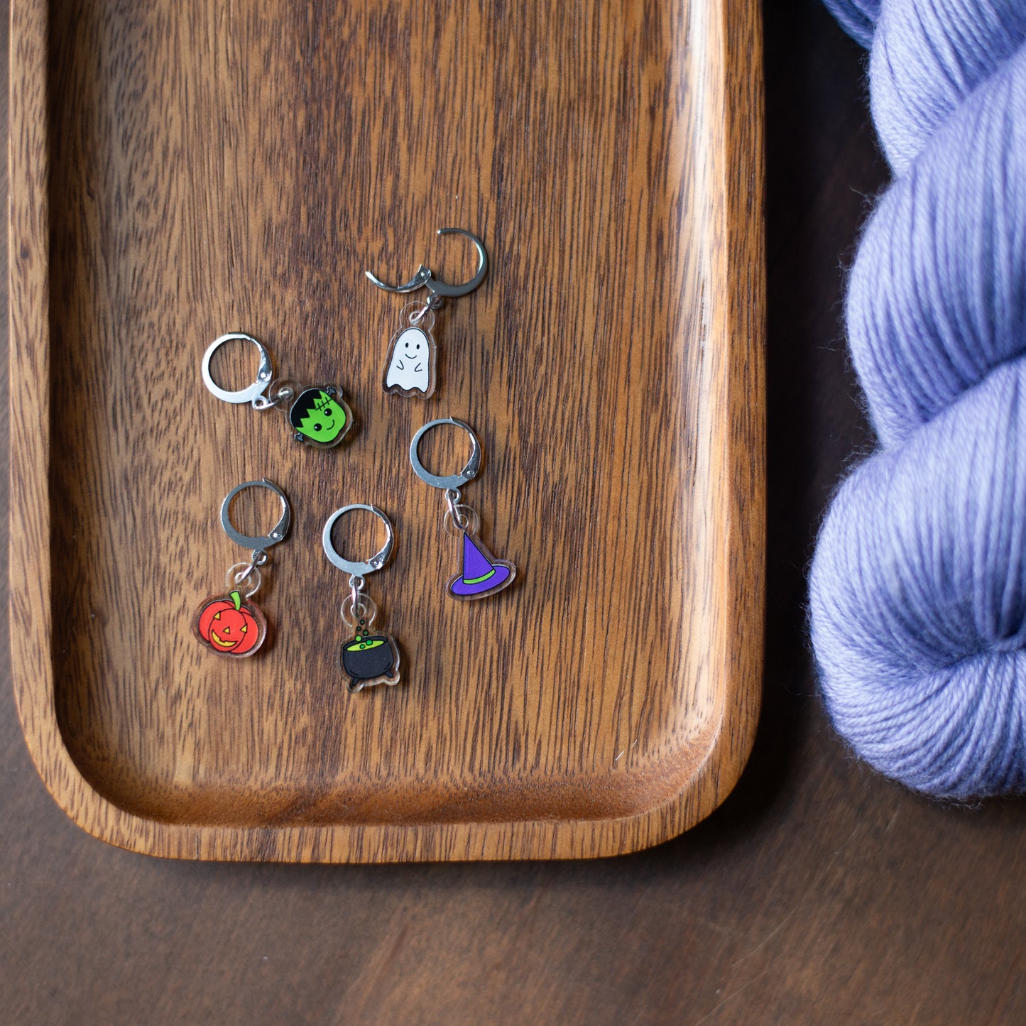 A set of Halloween stitch markers on a wooden tray