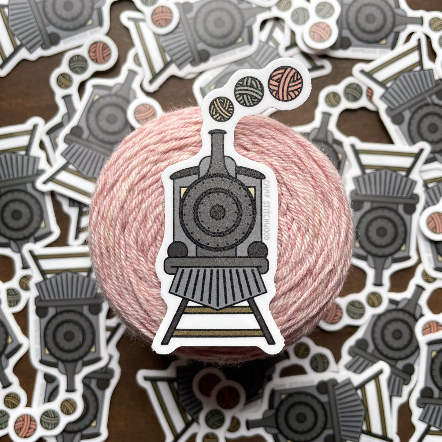Pink yarn ball with a steam locomotive sticker on a background of similar stickers