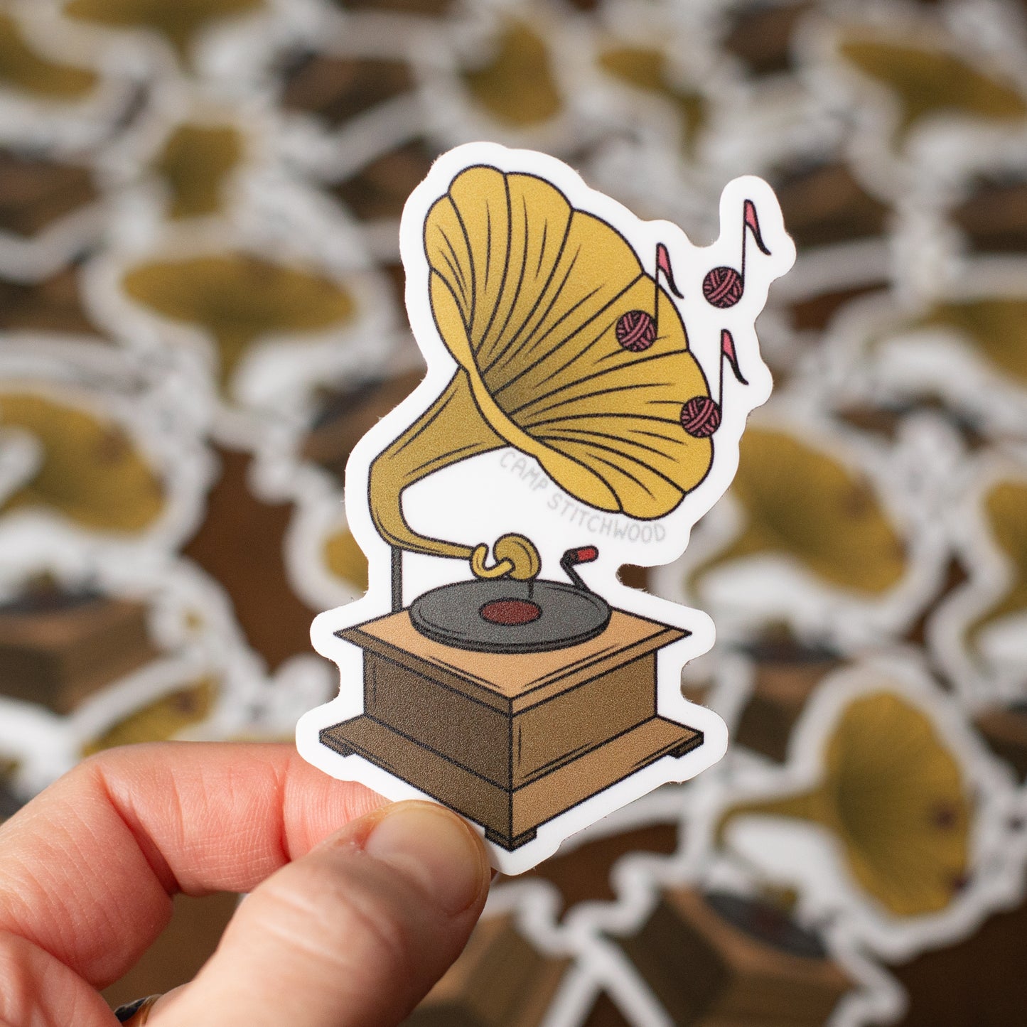 Sticker of a vintage gramophone held by a hand with a patterned background