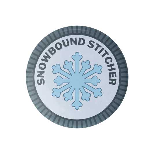 Circular merit badge with a snowflake and 'Snowbound Stitcher' text on a white background
