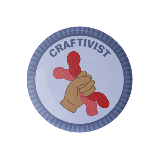 Circular badge with a hand holding red yarn, labeled 'Craftivist' on a white background.