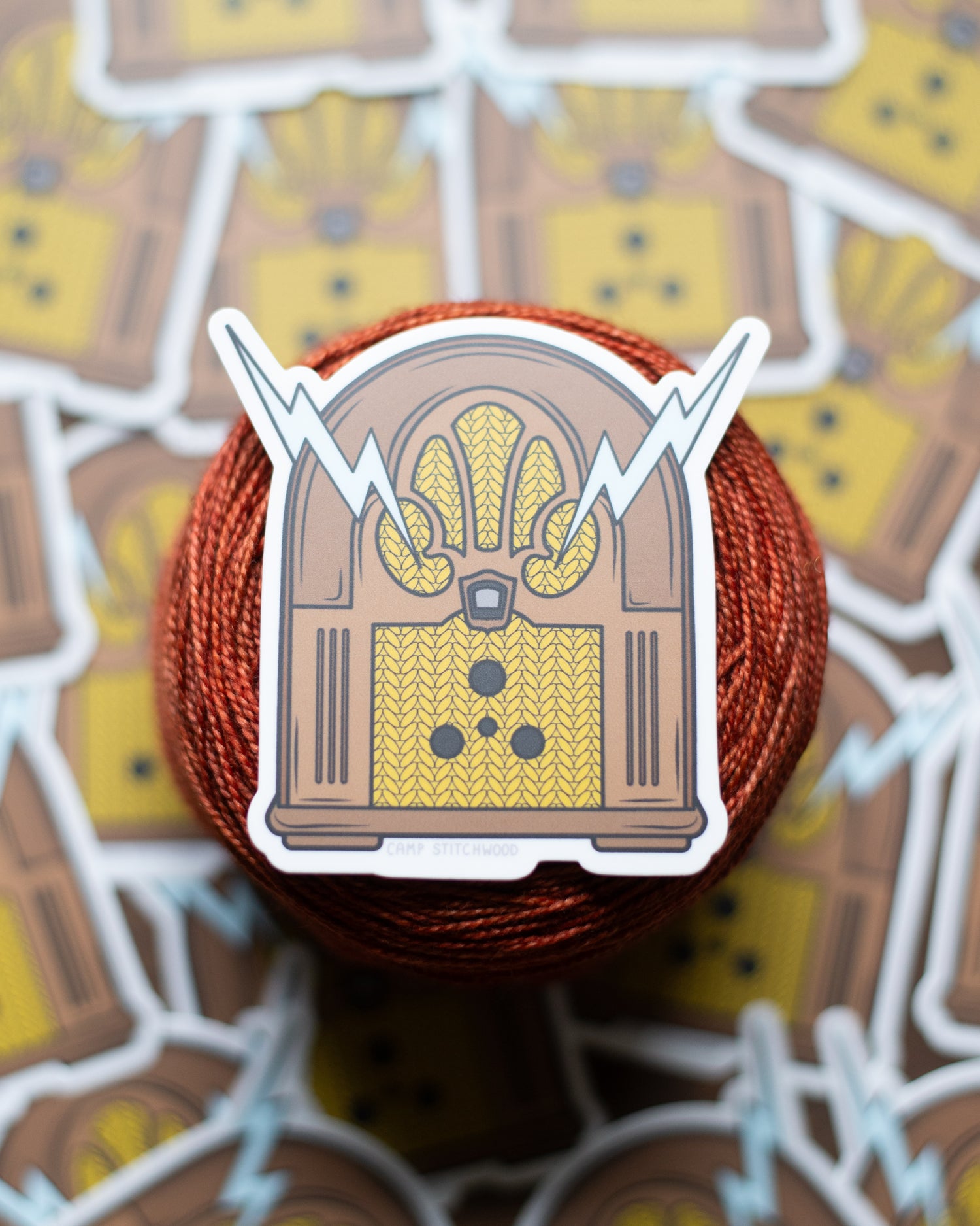Sticker of a vintage radio on a cake of yarn with more stickers in the background.
