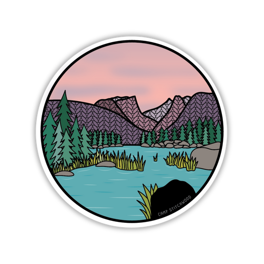 Round sticker with a nature scene of mountains, trees, and a lake.