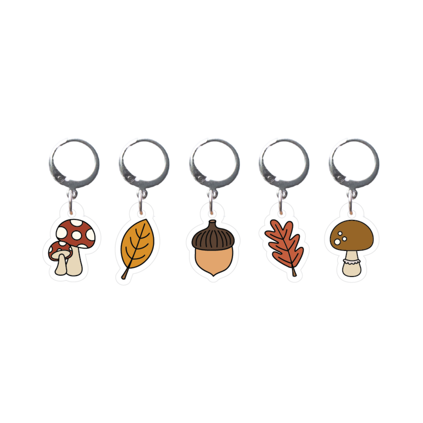 Set of five stitch markers with autumn-themed charms on a white background