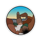 Round sticker with desert landscape design featuring rocks and a clear sky.