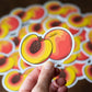 Hand holding a sticker with a peach design featuring yarn inside, against a background of similar stickers.