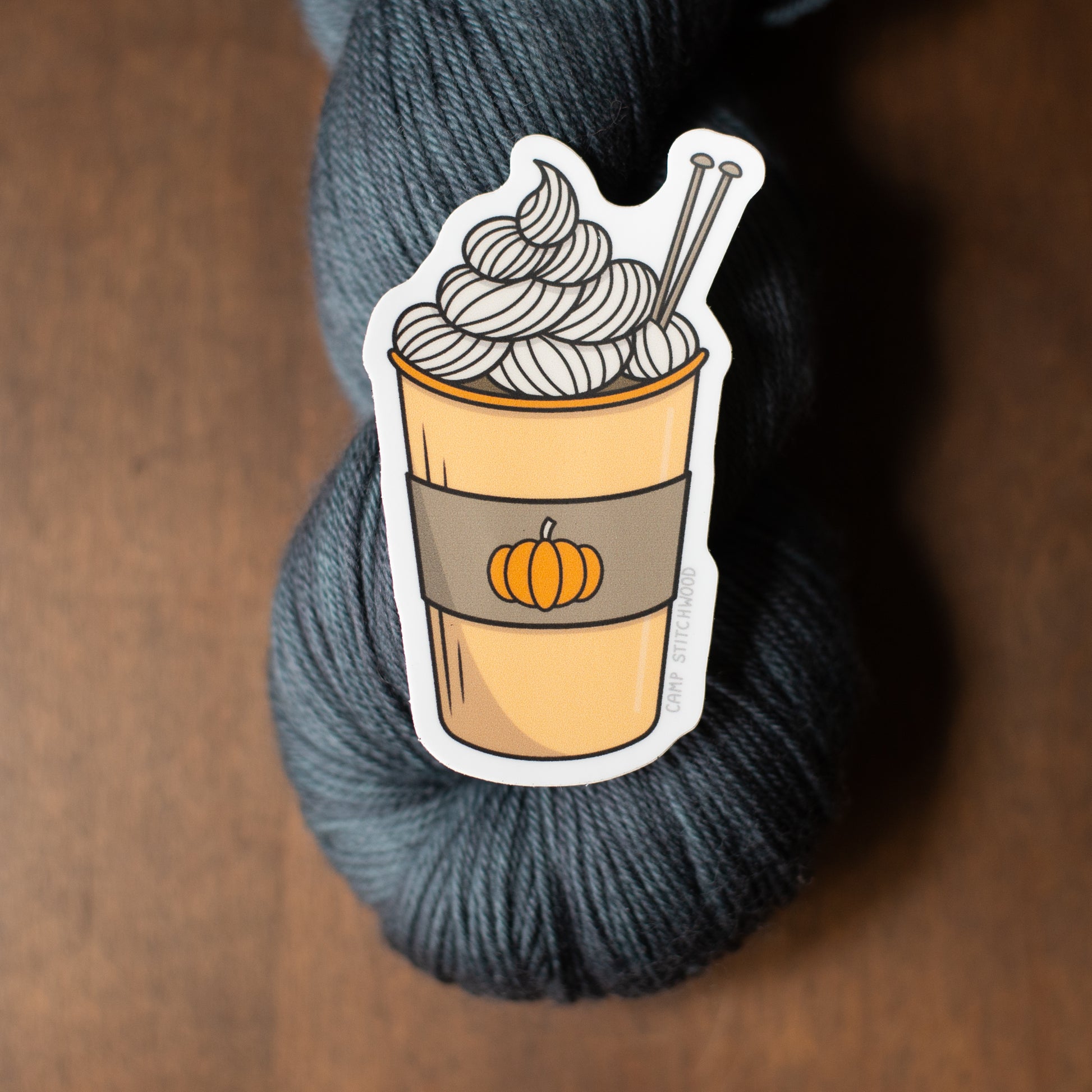 Yarn skein with a sticker of a pumpkin spice latte on a wooden surface