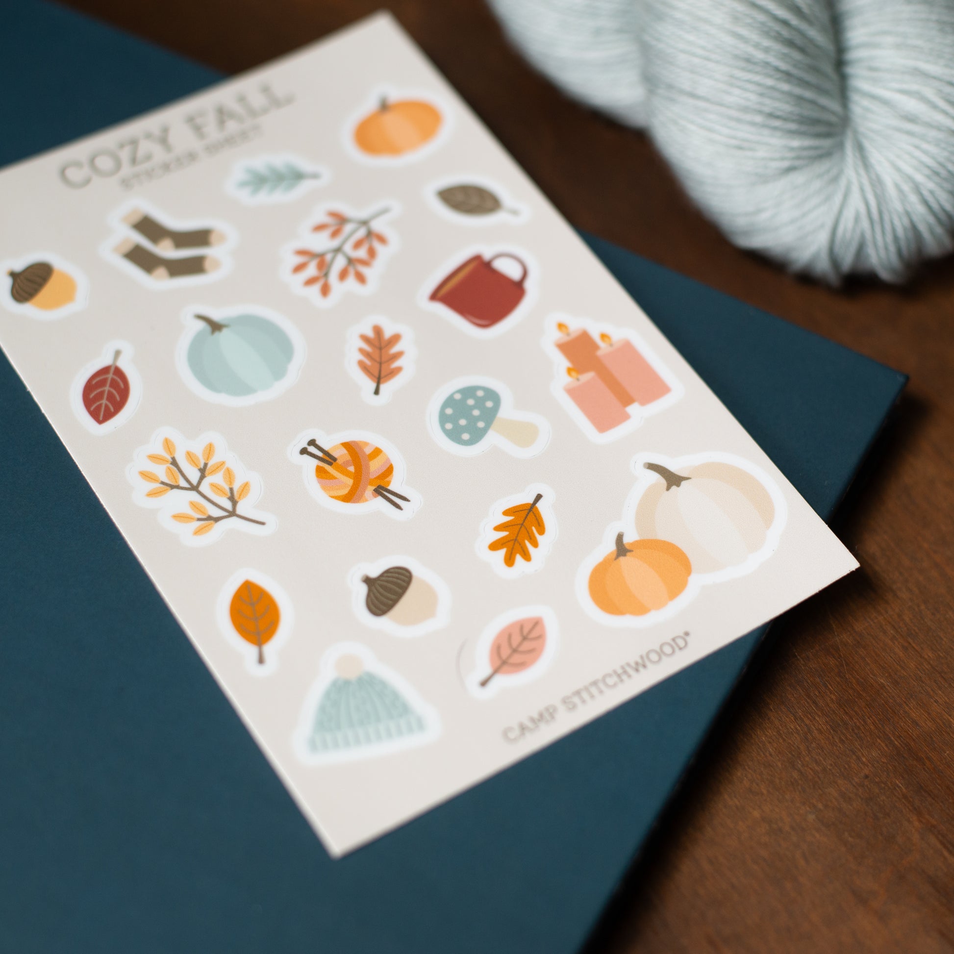 Sheet of fall-themed stickers with pumpkins, leaves, and other autumnal elements on a blue surface.