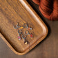 Wooden tray with fall forest stitch markers and yarn on a wooden surface