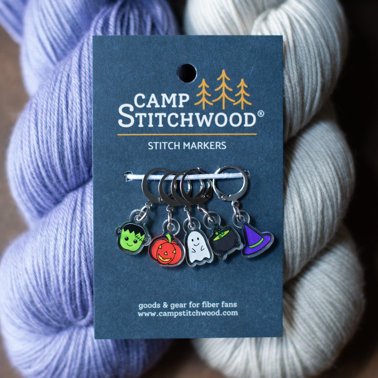 A set of Halloween stitch markers on purple and gray yarn