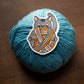 Blue yarn ball with a sticker of a cat playing with yarn on a wooden background