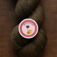 Brown skein of yarn with a 'Sip & Stitch' label on a brown background
