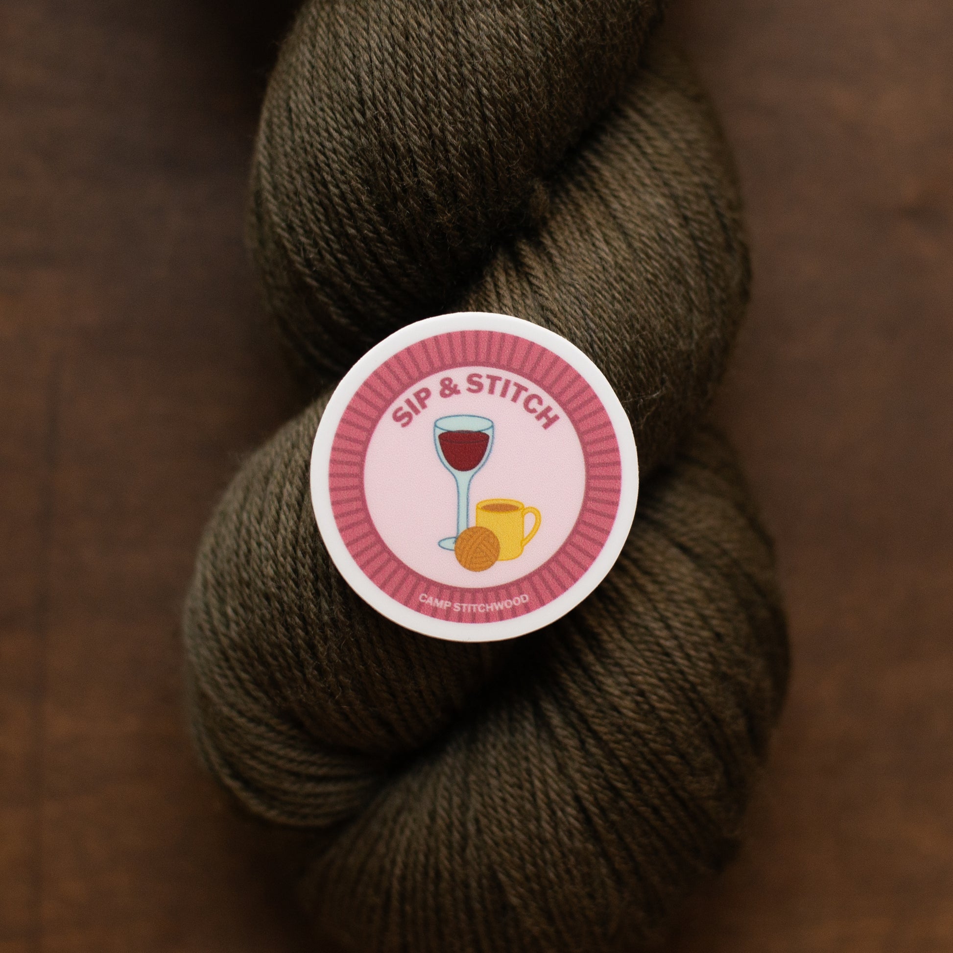 Brown skein of yarn with a 'Sip & Stitch' label on a brown background