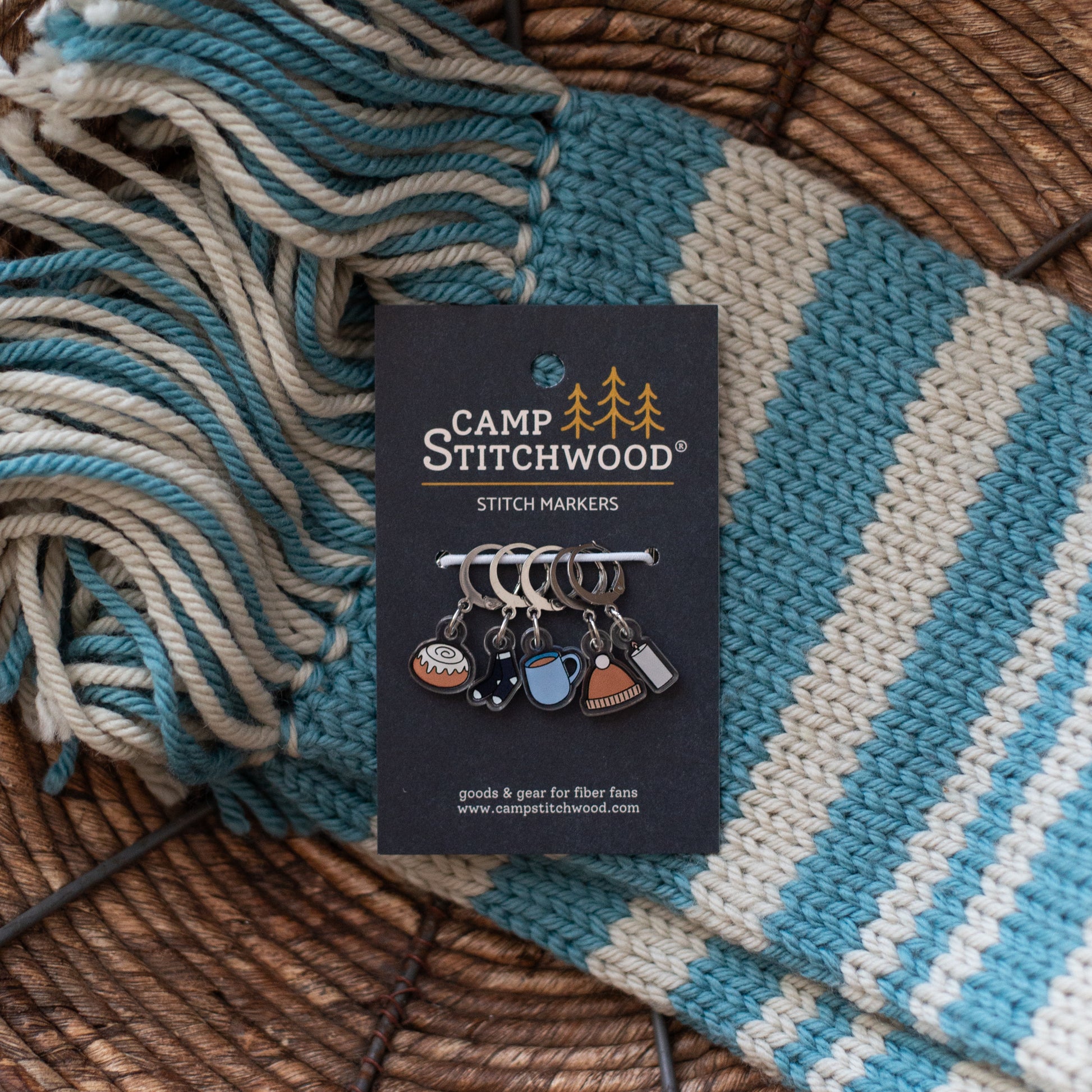 Camp Stitchwood stitch markers on a card with yarn in the background
