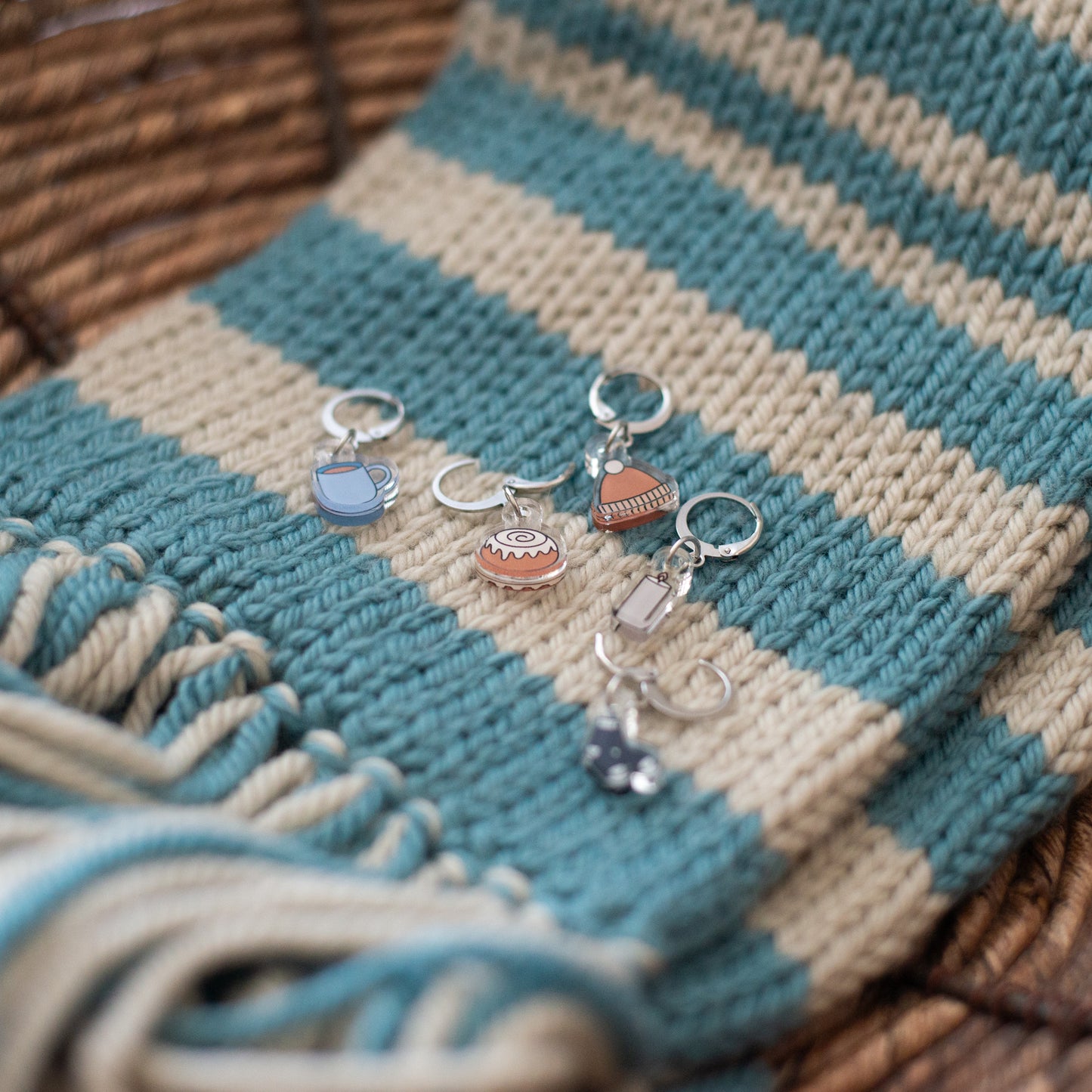 Stitch markers with charms on a striped fabric background