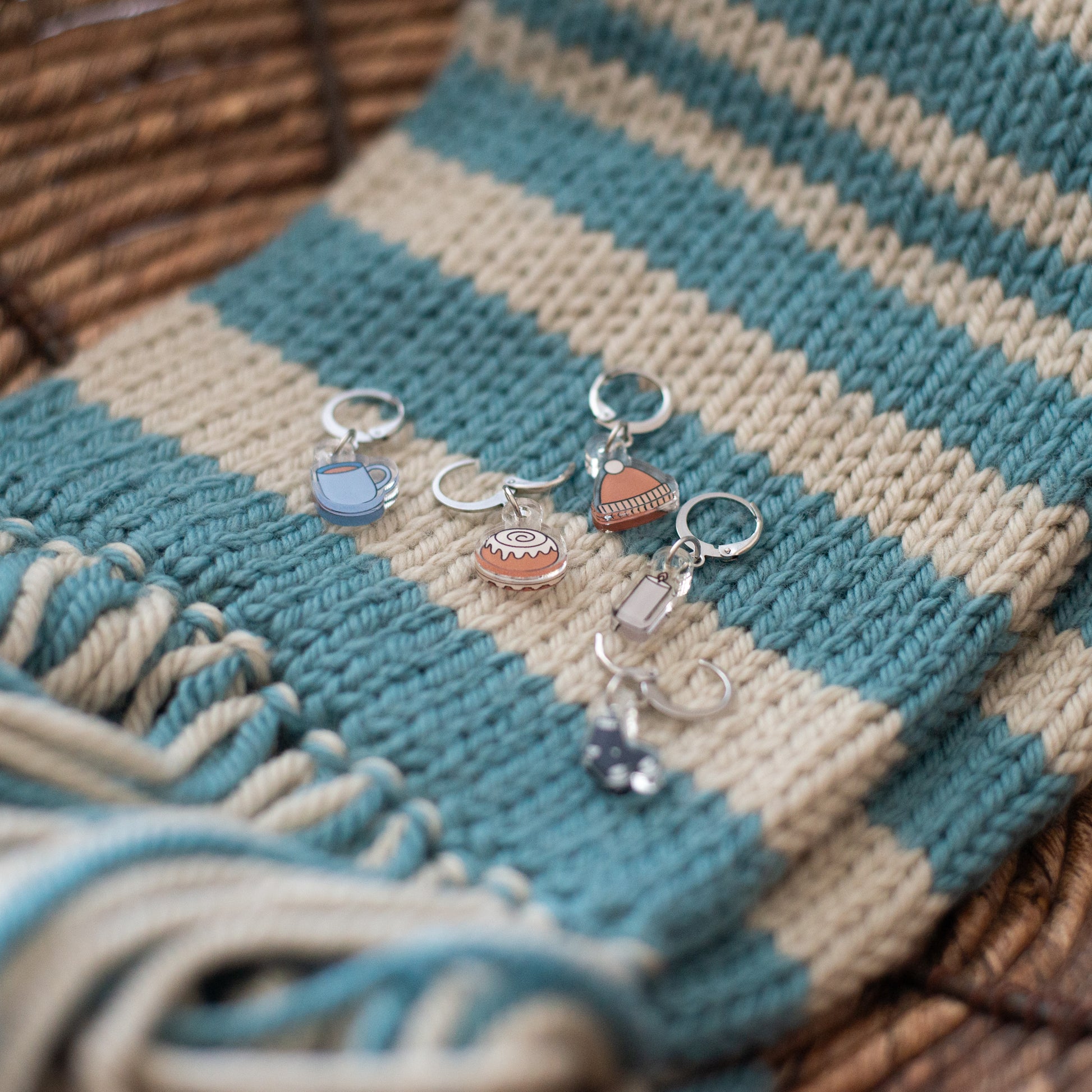 Stitch markers with charms on a striped fabric background