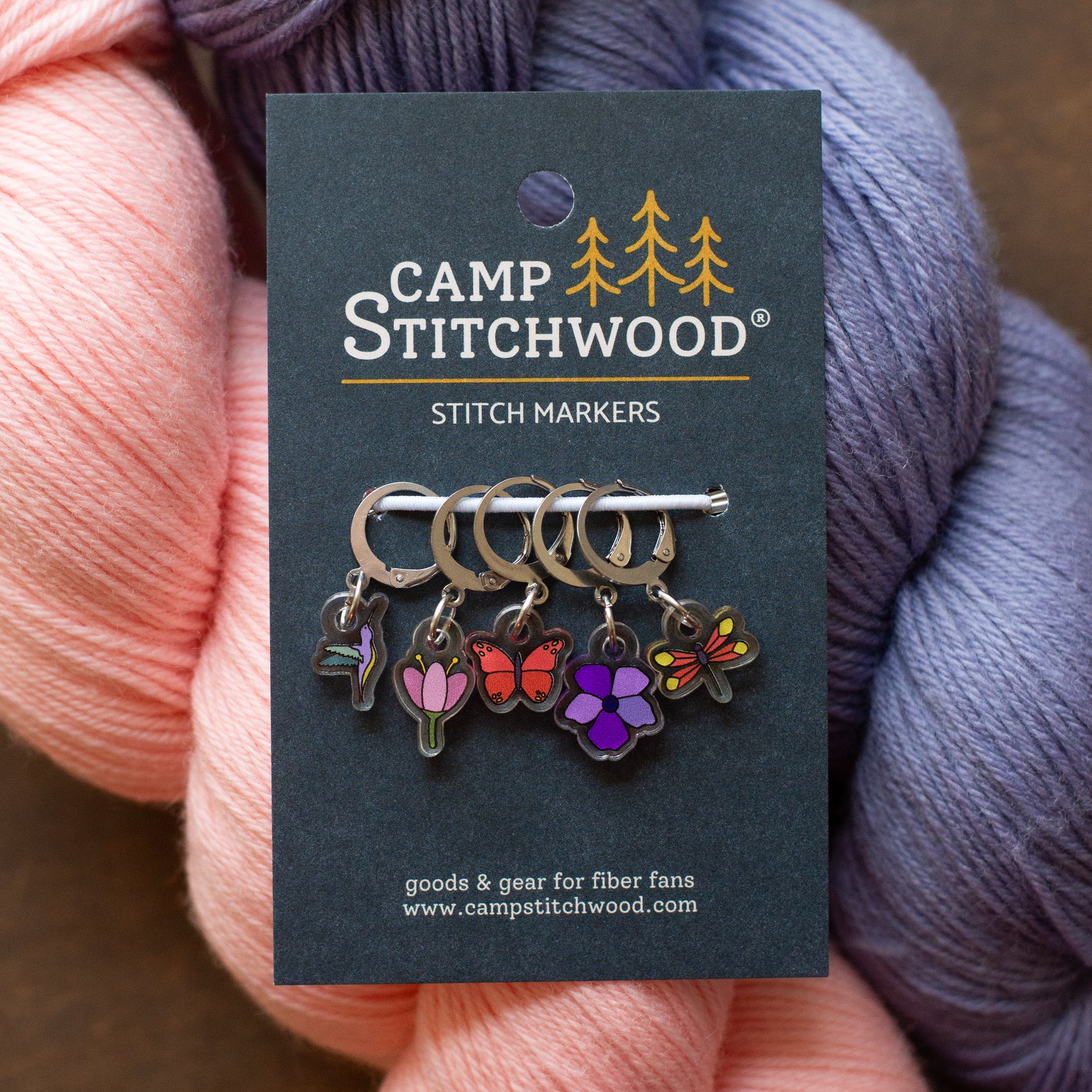 Camp Stitchwood stitch markers on a card with yarn in the background