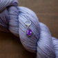 Purple yarn with a floral charm on a brown background