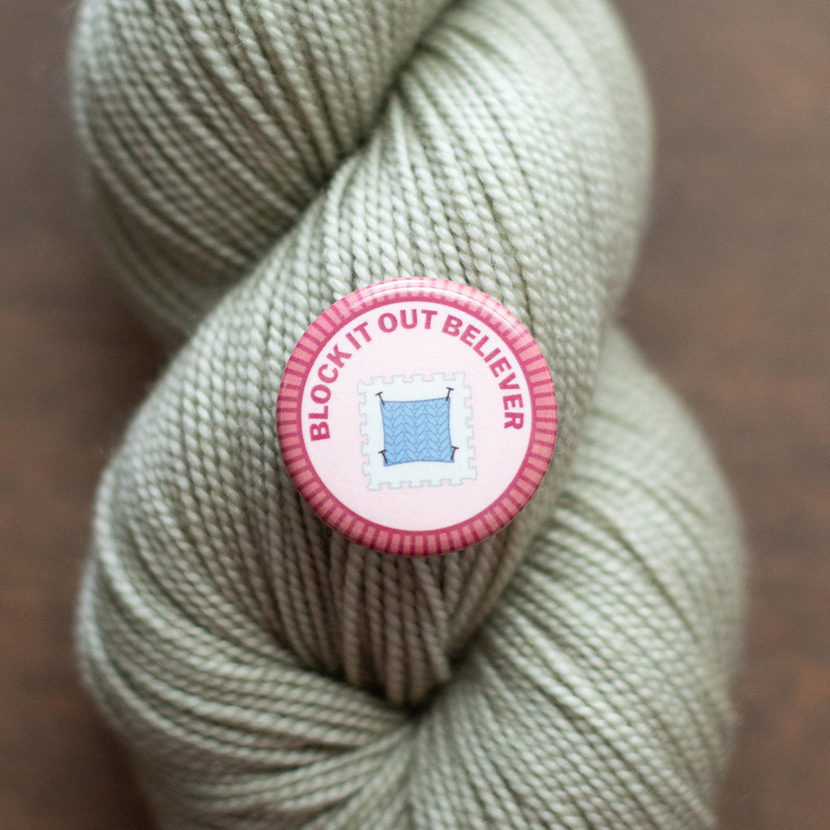 a Block it out believer badge on light green yarn