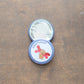 Craftivist badge on top of an upside down badge