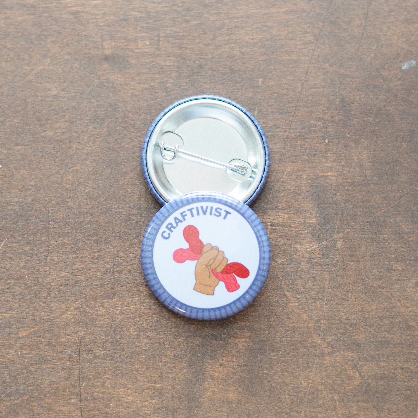 Craftivist badge on top of an upside down badge