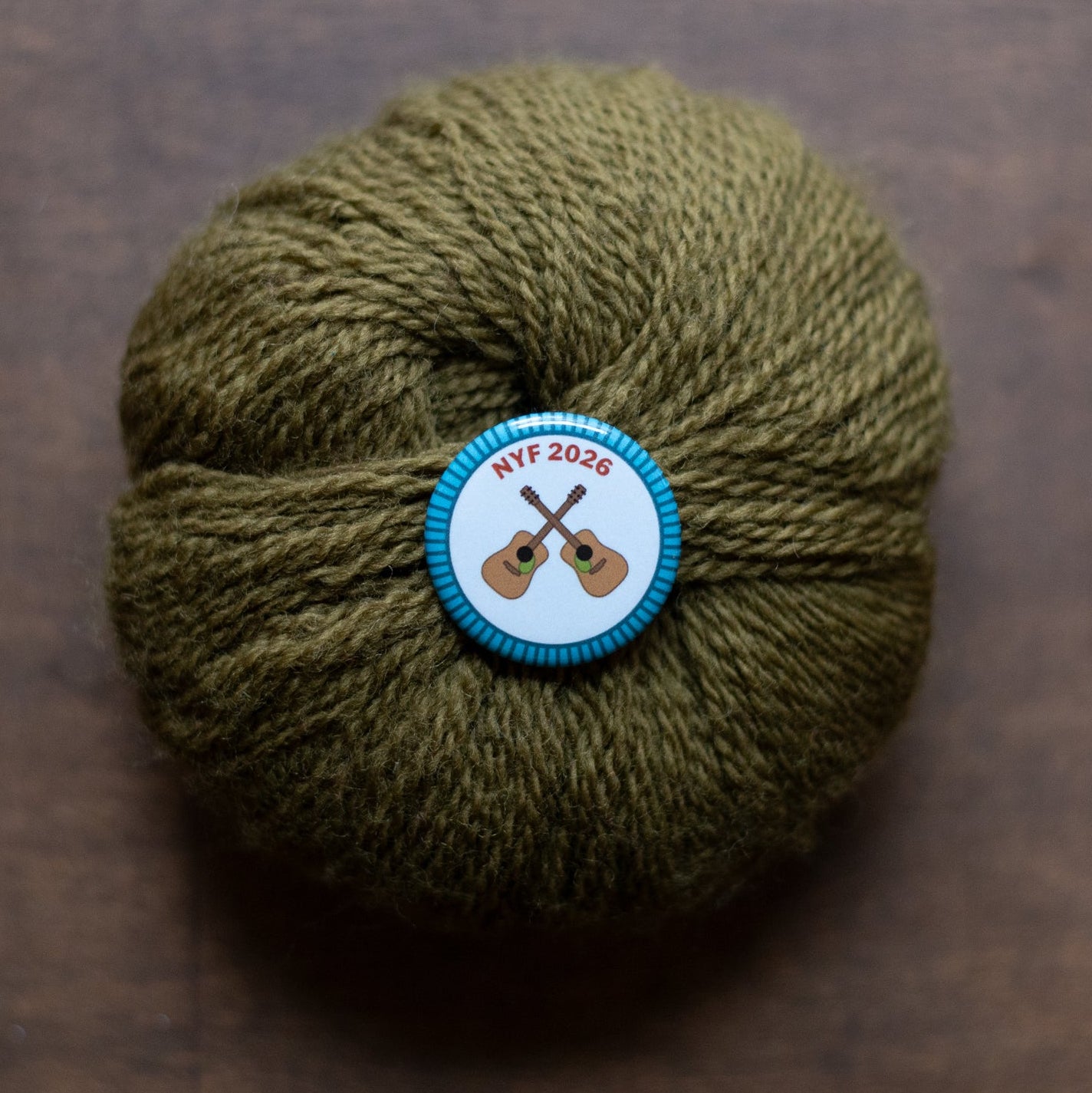 Ball of green yarn with a badge on a brown surface