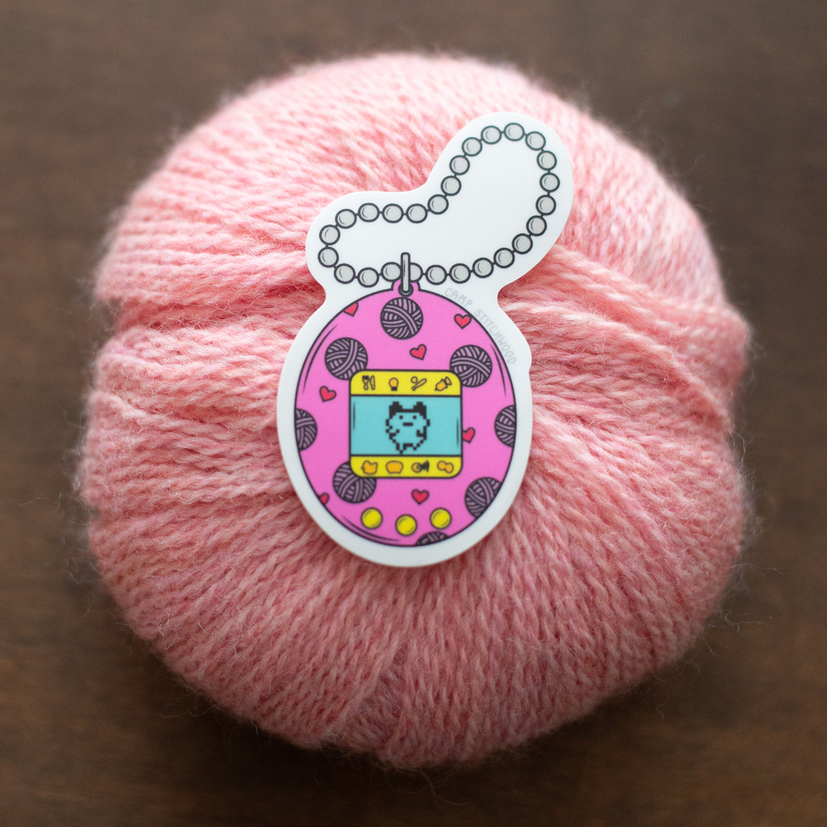 A pink digital pet sticker on a pink ball of yarn