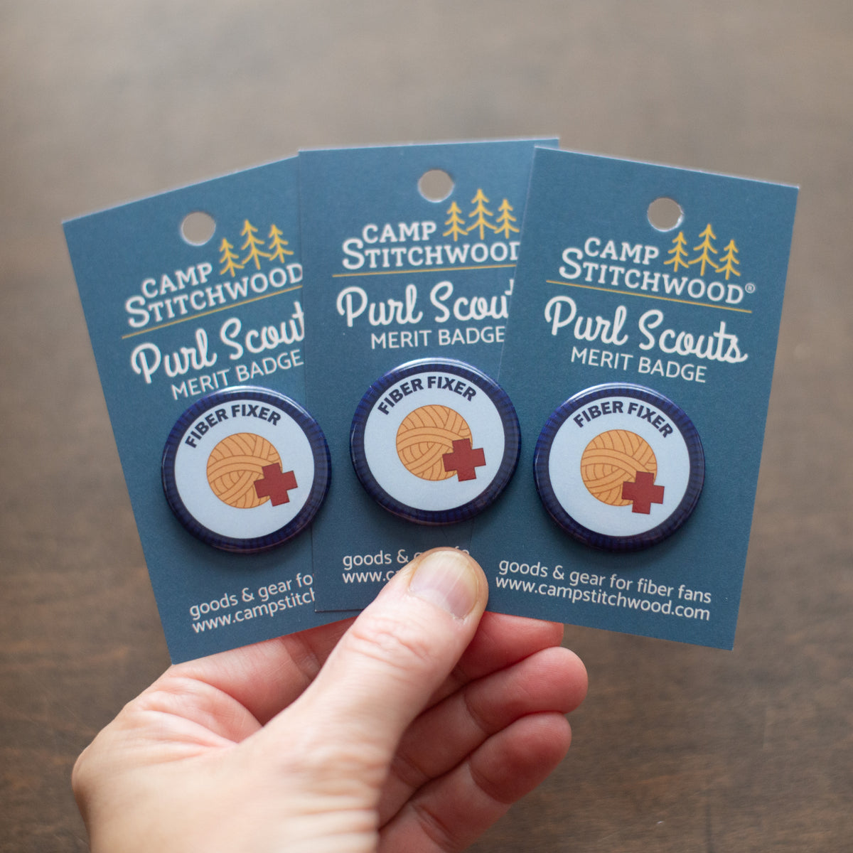 a hand hold three fiber fixer badges