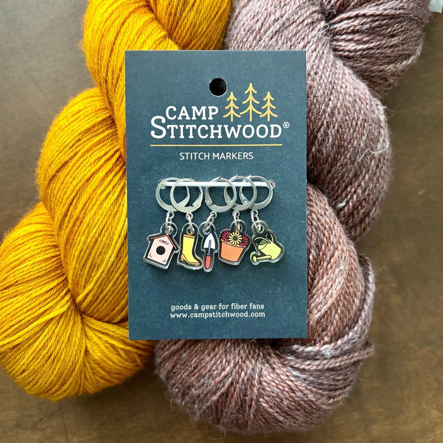 Camp Stitchwood stitch markers on a card with two skeins of yarn.