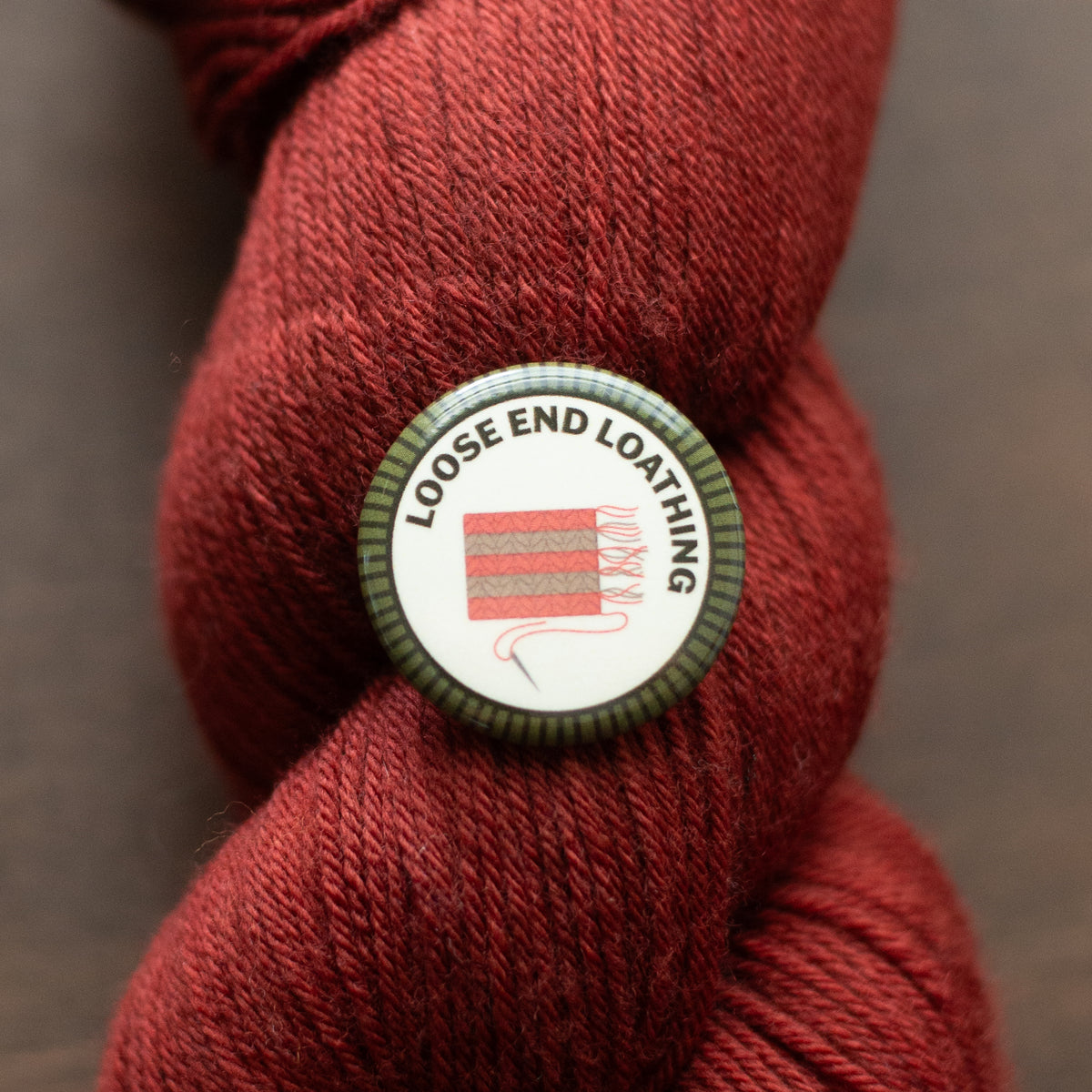 a Loose End Loathing badge on red yarn