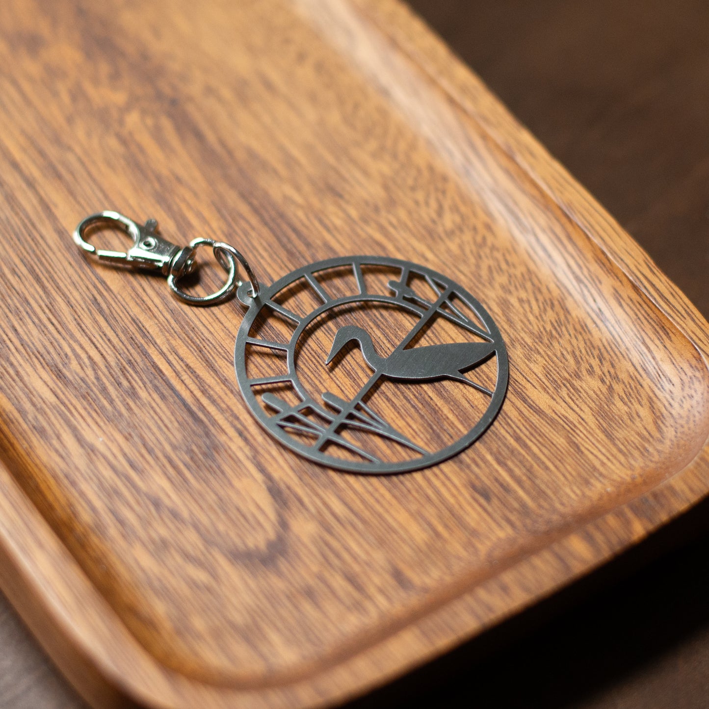 Metal stitch marker holder with bird design on a wooden surface
