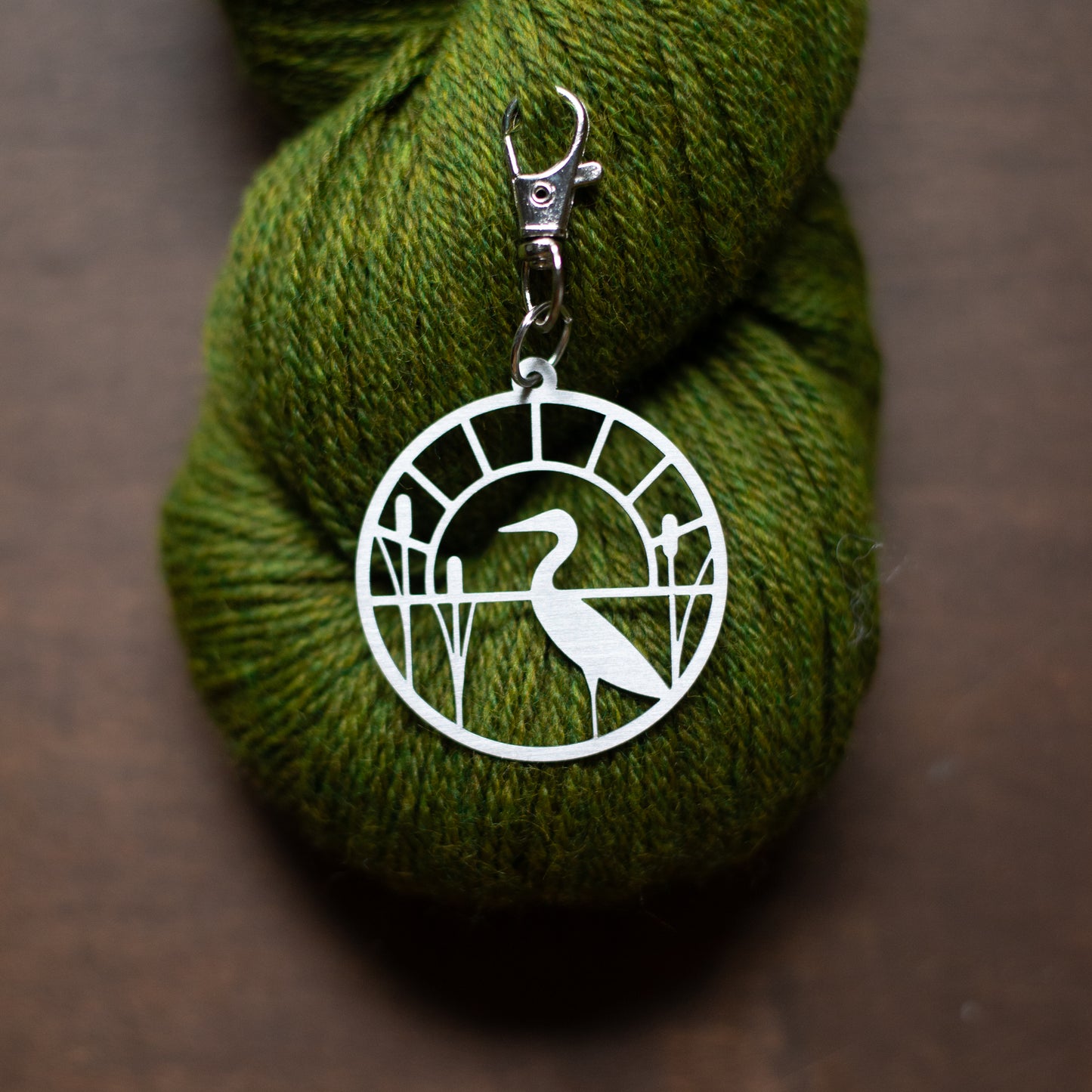 Metal stitch marker holder on green yarn