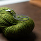 Metal stitch marker holder on green yarn