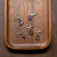Five stitch markers with various charms on a wooden surface