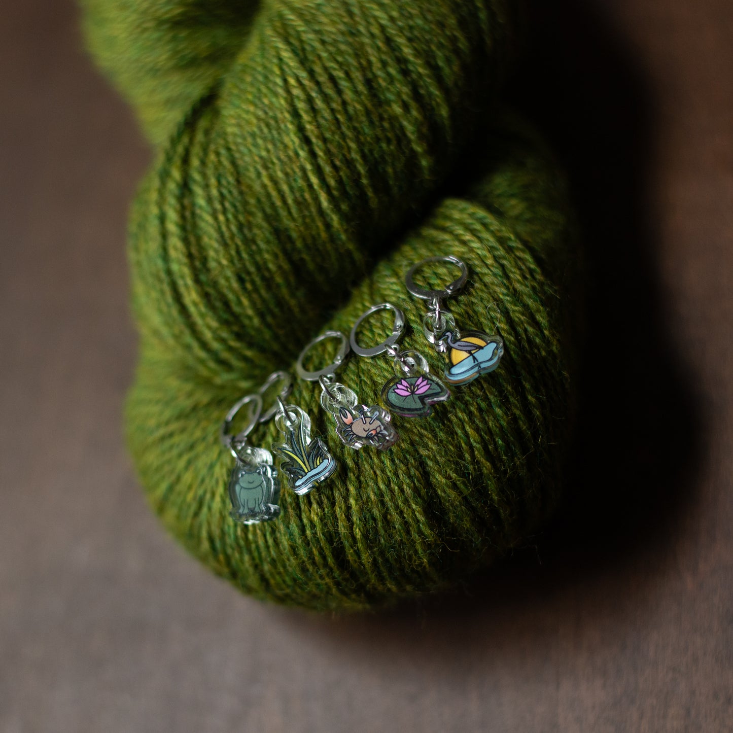 Set of colorful stitch markers on a hank of green yarn