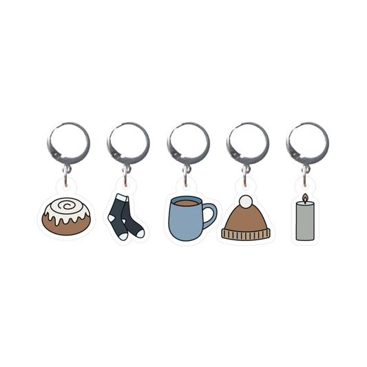 Set of five stitch markers with different charms on a white background