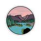 Round sticker with a nature scene of mountains, trees, and a lake.